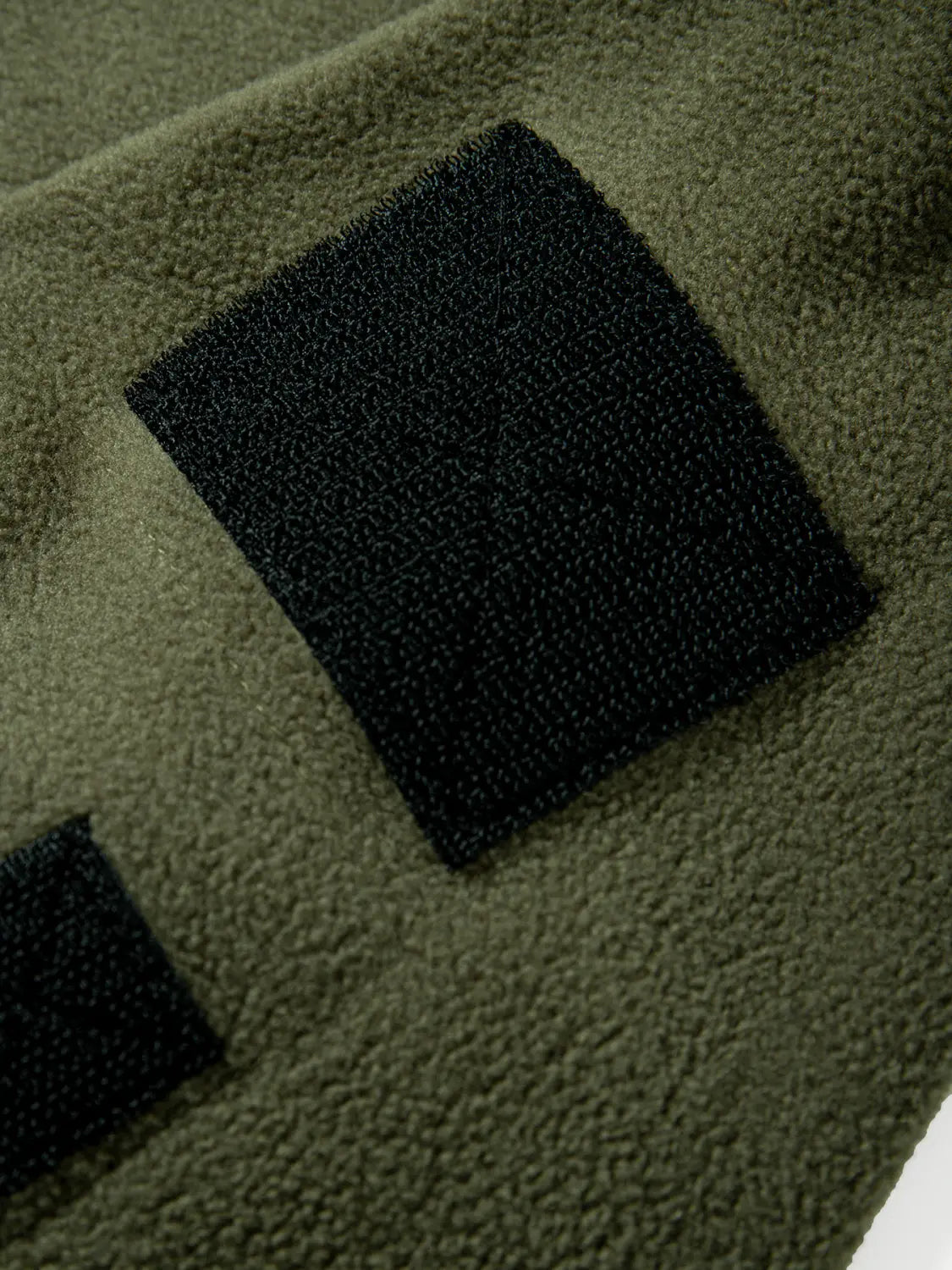 Chaqueta polar táctica para hombre, con tejido de polar verde oliva, parches negros de velcro y diseño con capucha y cremallera completa.