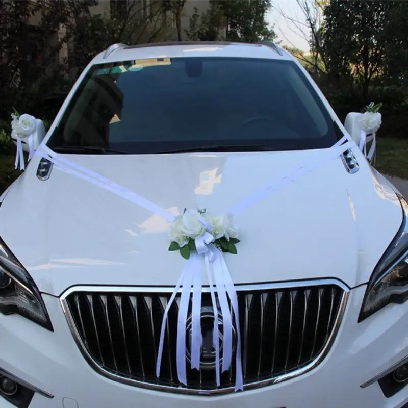 Voiture de mariage blanche décorée de délicates compositions florales artificielles blanches et de rubans provenant de l’ensemble de décoration florale artificielle pour voiture de mariage.