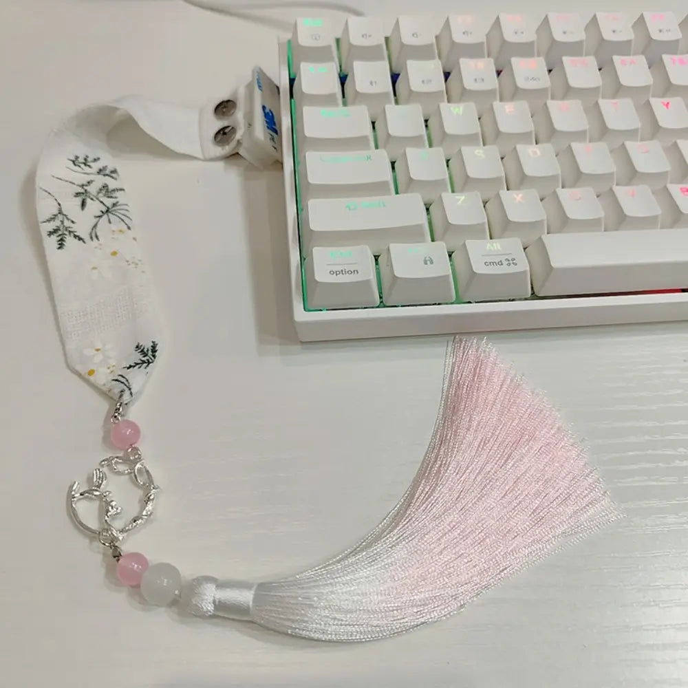 Sangle personnalisée pour le modèle Ribbon Dragon du clavier Wooting, comprenant un porte-clés délicat en tissu blanc avec broderie botanique noire, perles roses et translucides, un fermoir métallique à tons argentés et un pompon rose poudré.