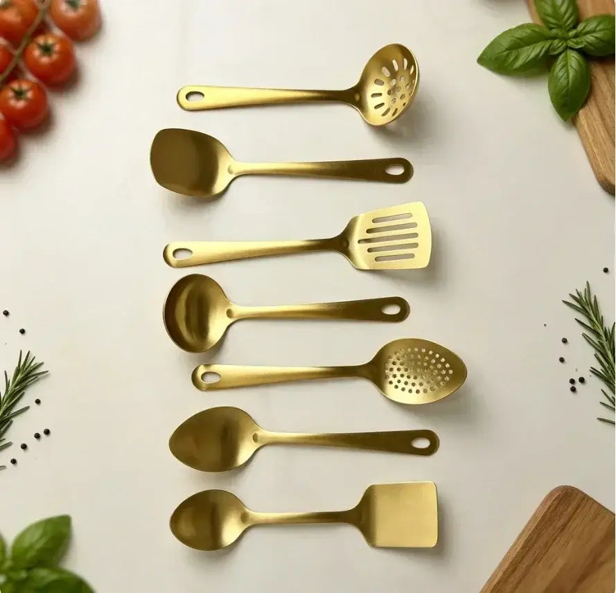 Set of seven gold-colored stainless steel kitchen utensils with sleek modern handles including slotted spoons spatulas ladles and a solid spoon for cooking.