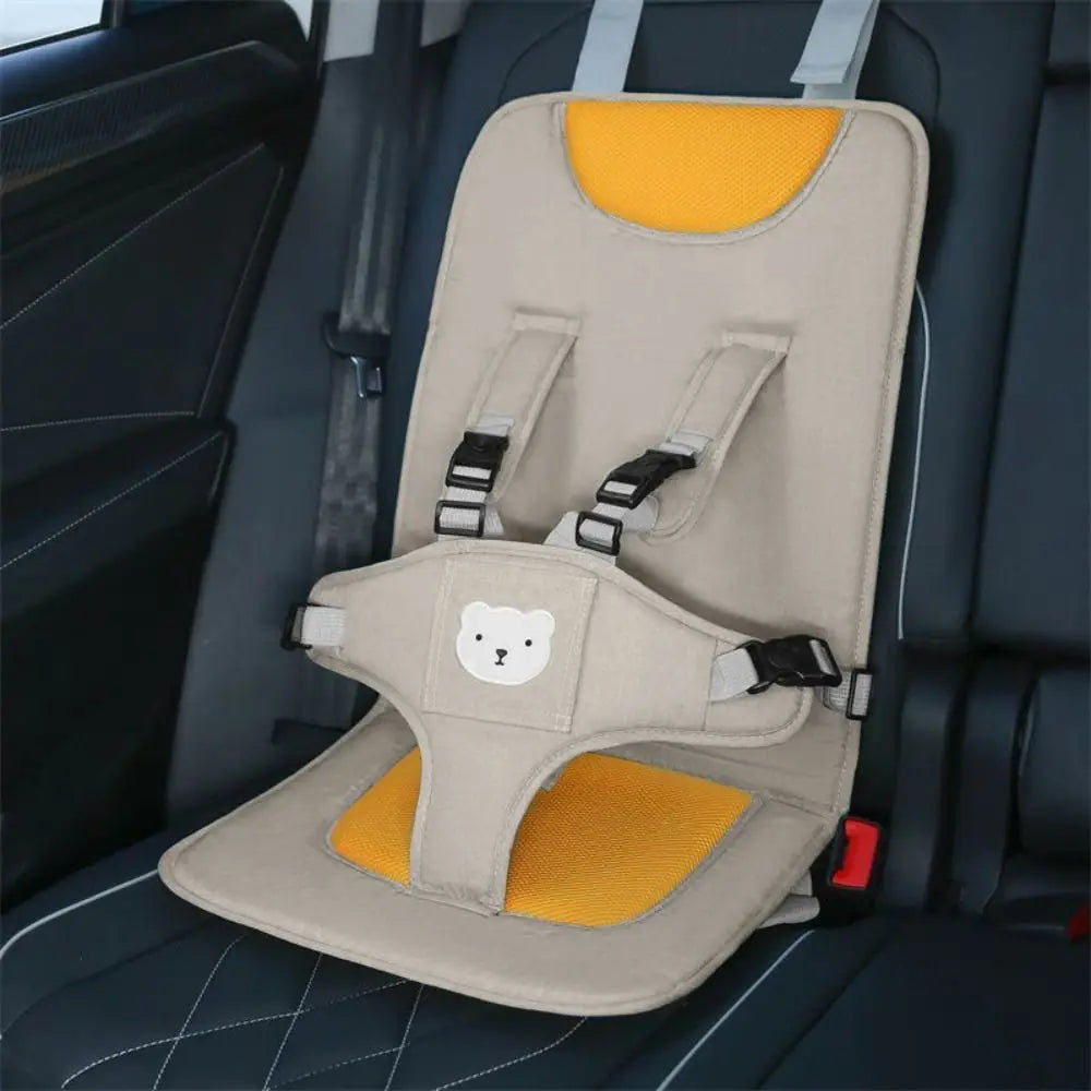 Beige- und gelbes tragbares Baby-Autokindersitzerhöhungskissen mit einem Sicherheitsgurt und einem weißen Bärengesicht-Patch.