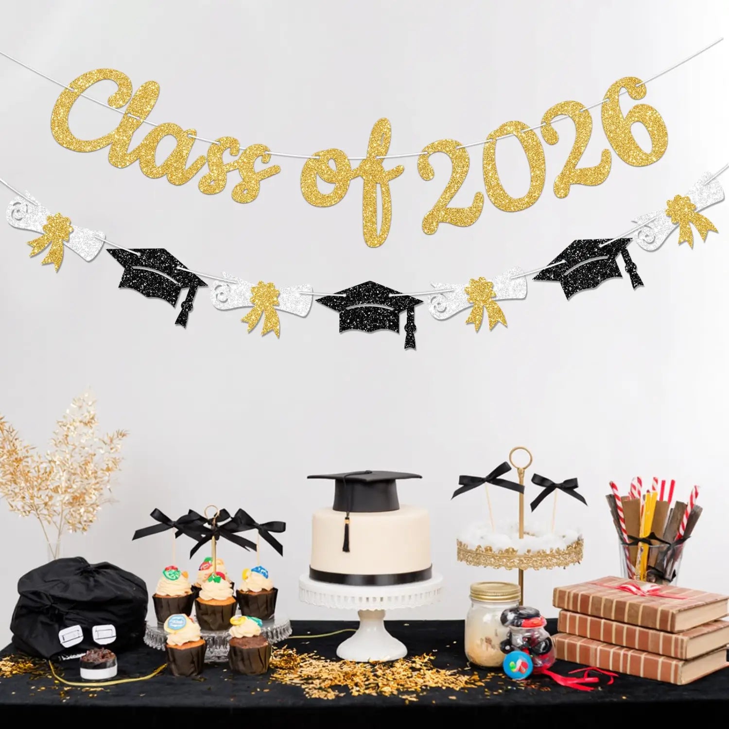 class of 2026 graduation banner and garland featuring gold glitter lettering with black and white graduation cap cutouts.