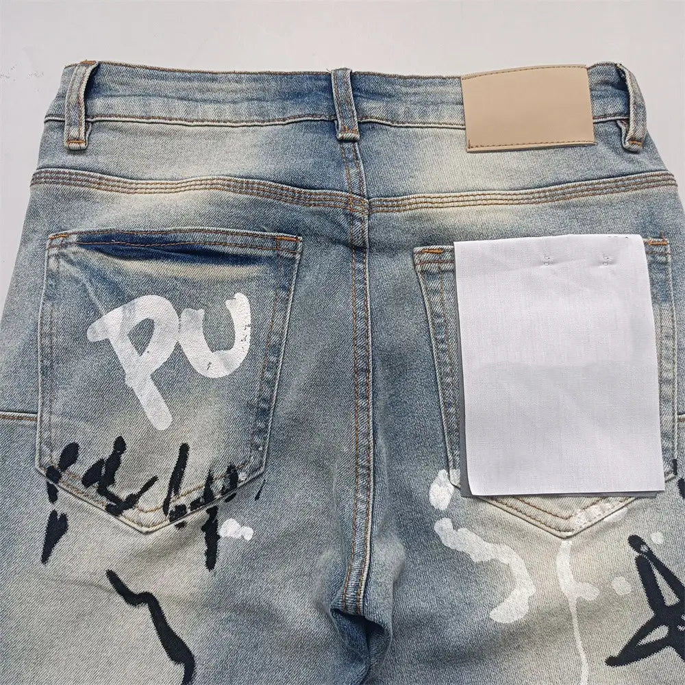 Jeans skinny déchirés pour hommes, effet délavé rétro vintage bleu, denim à lavage clair, avec marquages de peinture au spray style graffiti blanc et noir sur les poches arrière, montrés depuis le côté arrière.