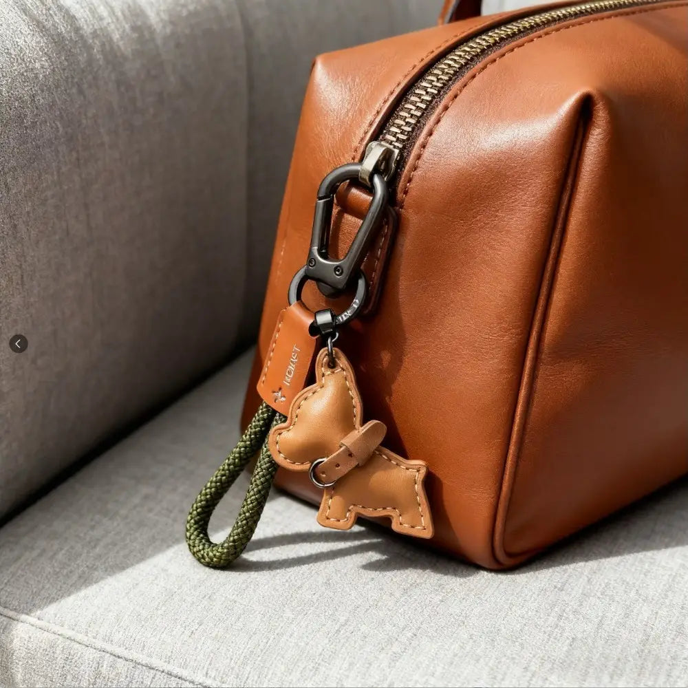 French bulldog leather keychain in tan featuring a stitched dog charm with an olive green braided cord and black metal carabiner.