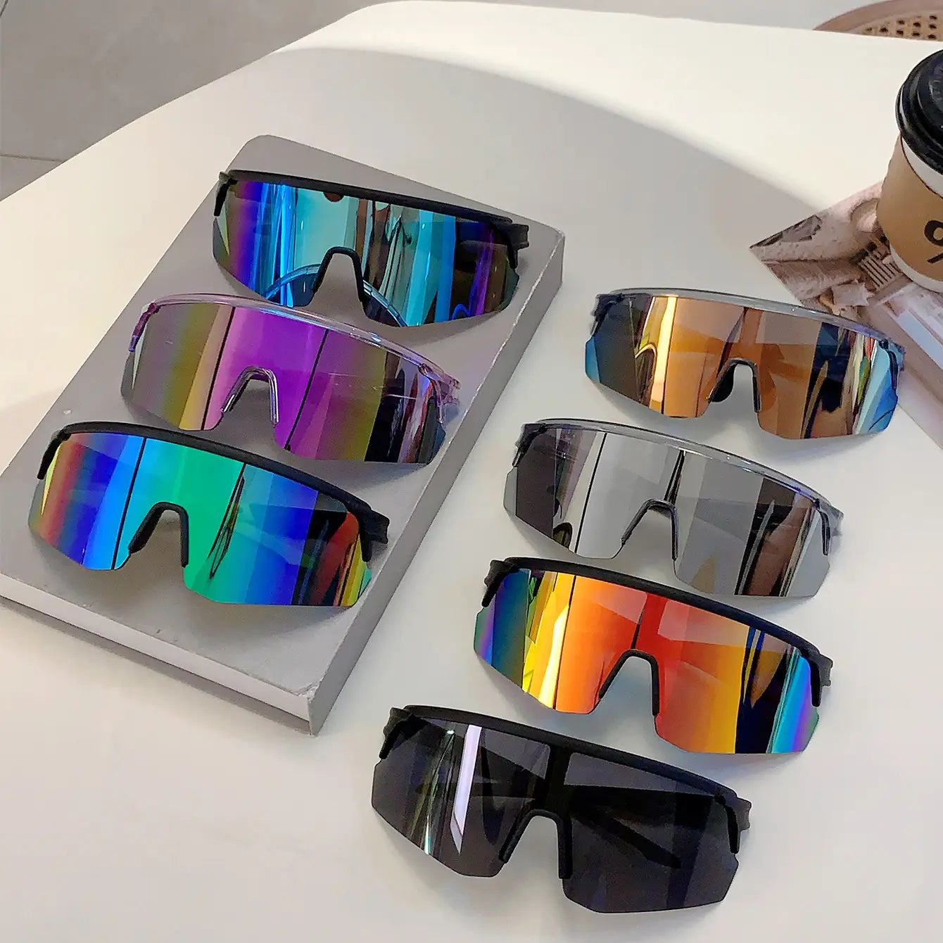 Ensemble de six lunettes de soleil de sport surdimensionnées, avec des montures noires élégantes et des verres miroirs arc-en-ciel irisés vibrants, conçues pour le cyclisme.