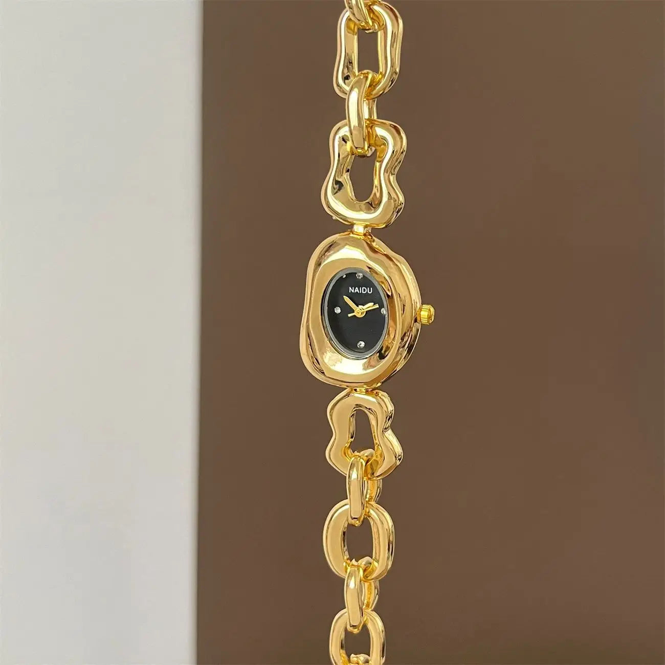 Gold chain link vintage wristwatch featuring a gold-toned Naidu watch with a black dial and ornate sculptural chain links.