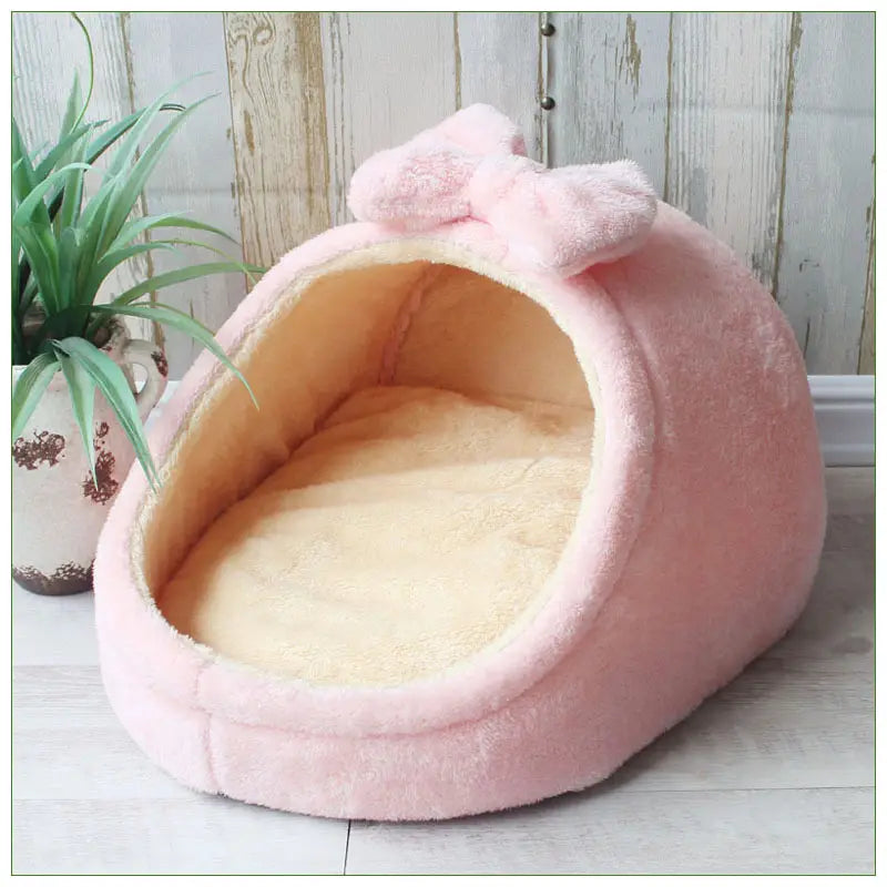 pink plush foldable pet cave bed for small dogs and cats with a matching bow and soft cream-colored interior lining