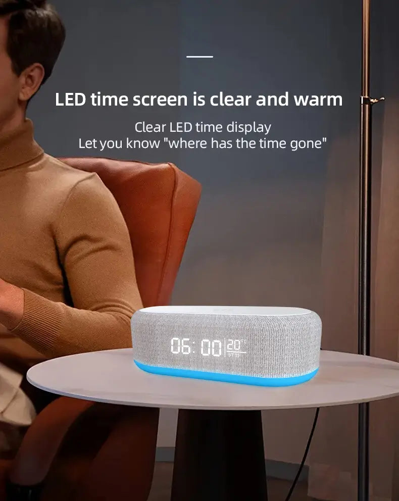 Réveil à haut-parleur Bluetooth en tissu gris avec charge sans fil, finition texturée blanche et afficheur d’heure à LED bleue lumineuse indiquant 06 00 ainsi que la température, doté d’une fonction de charge sans fil et d’un mode d’économie d’énergie.
