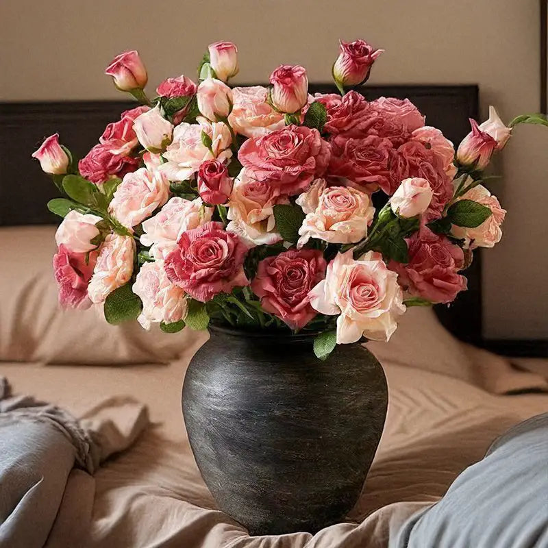 Eine frontale Ansicht eines verwelkten Stielrand-Rosenstraußes mit rosa- und cremefarbenen Rosen, angeordnet in einer mattschwarzen Keramikvase für französische Vintage-Heimdekoration.