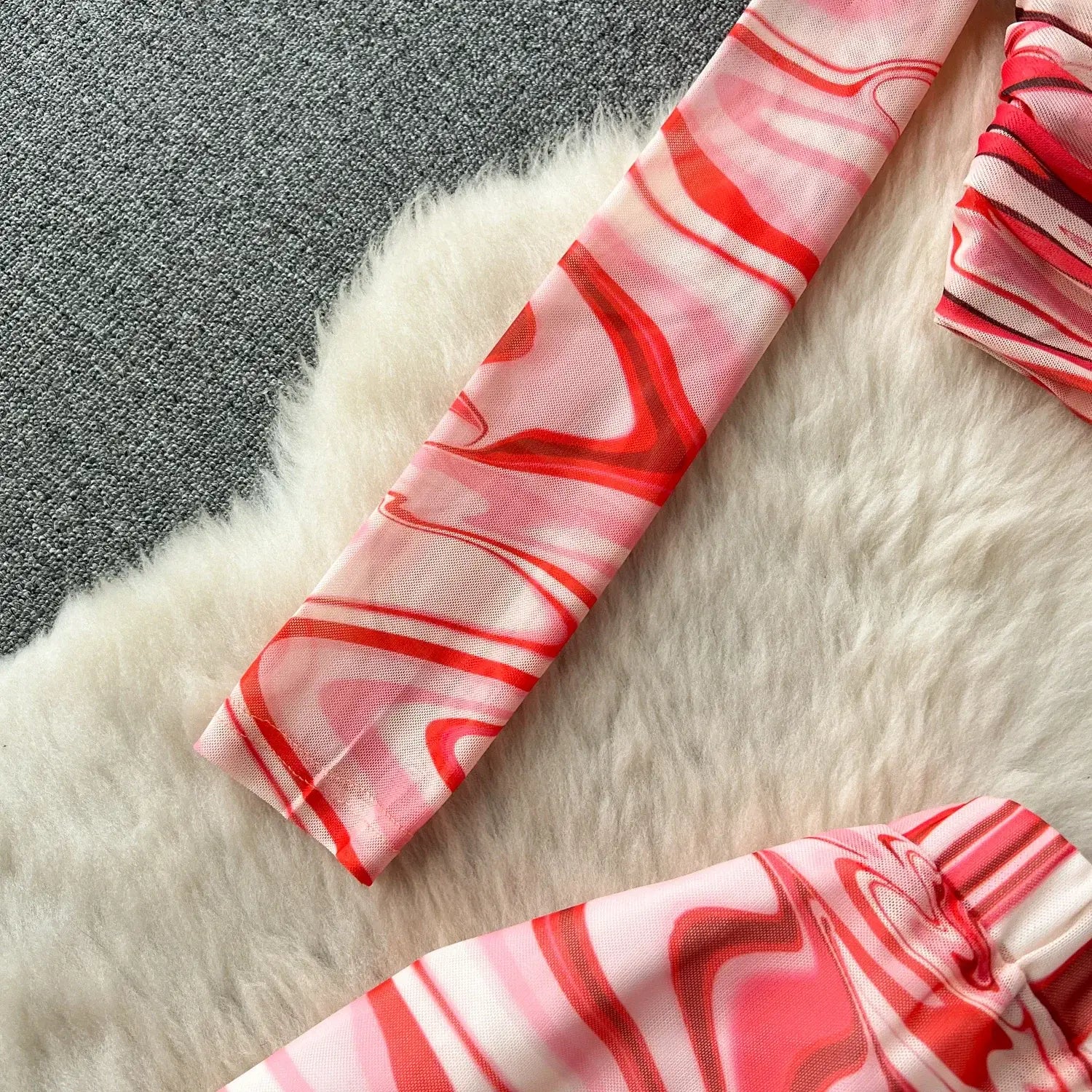 a vibrant red and pink marbled patterned fabric sleeve from a two piece mesh skirt set marble print featuring elastic closure type
