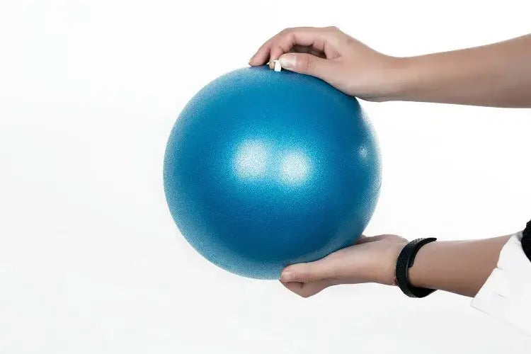 A vibrant blue textured anti-burst yoga ball held gently in two hands designed for balance training with air leakage resistance.