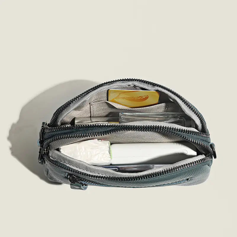 Graue Kulturbeutel-Tasche aus echtem Leder mit schwarzen Reißverschlüssen und mehreren Fächern, entworfen für organisierten Reisegebrauch