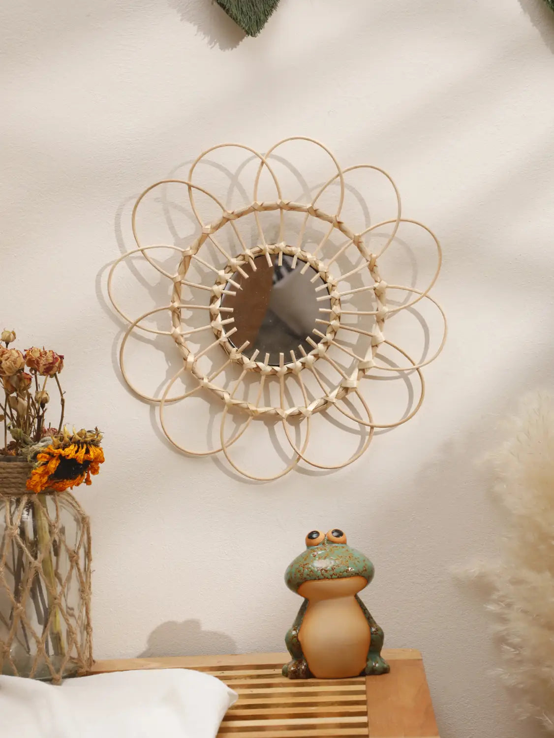Ein rundes Wandspiegel-Exemplar mit einem zarten cremefarbenen, gewebten Rattan-Sonnenstrahl-Rahmen, der die ästhetische Gestaltung des Raums wirkungsvoll unterstreicht.