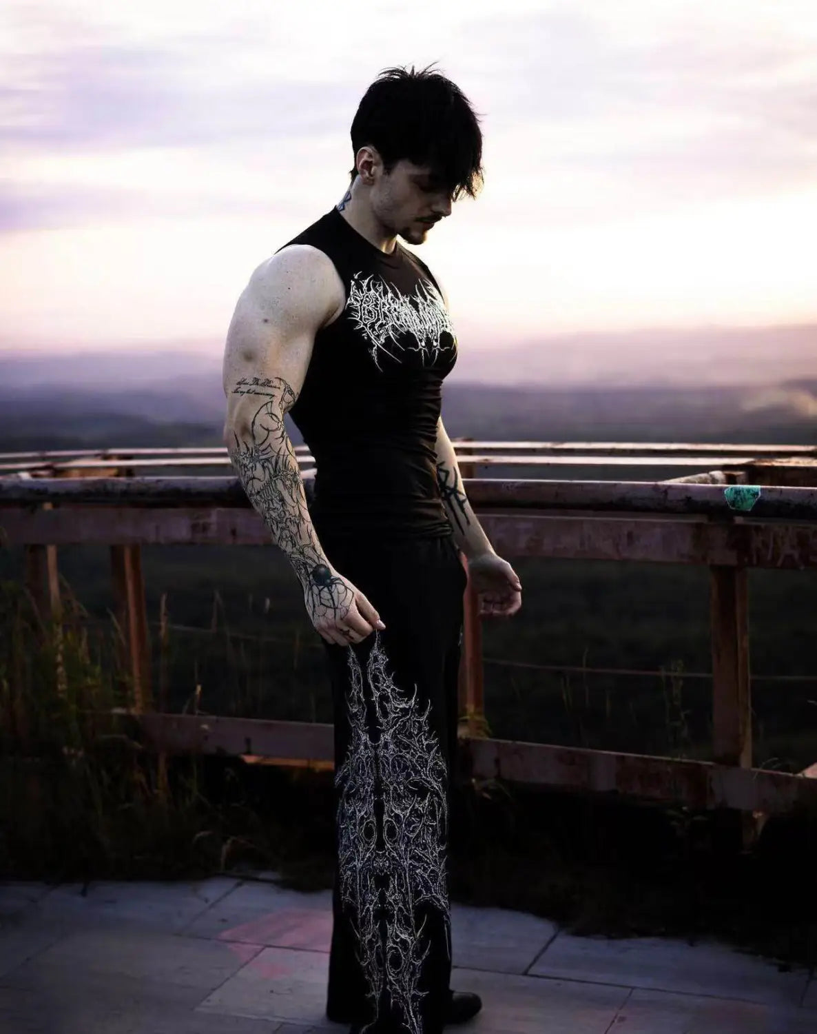 Camiseta sin mangas negra de fitness con bordado blanco intrincado estilo gótico a través del pecho, diseñada como camisole deportiva de secado rápido para uso en fitness.