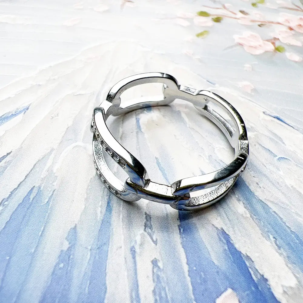 Ring aus Sterlingsilber-Gliedern mit Zirkonia, mit schlankem, silberfarbenem Metall und modernem offenem Glieddesign, mit dezent eingearbeiteten Steinen.