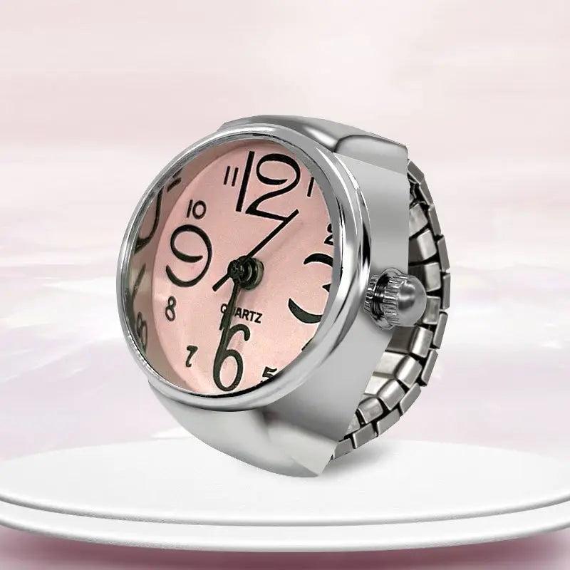 A sleek silver-toned quartz ring watch with a pink face and bold black numerals designed as finger couple jewelry.