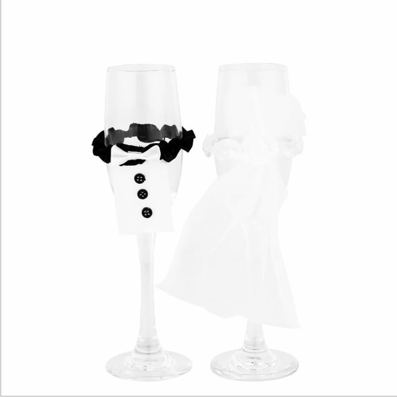 Copas de champán de cristal transparentes con cubiertas de esmoquin de tela negra y moño de lazo negro, procedentes del juego de cubiertas de copas de vino para la novia y el novio.