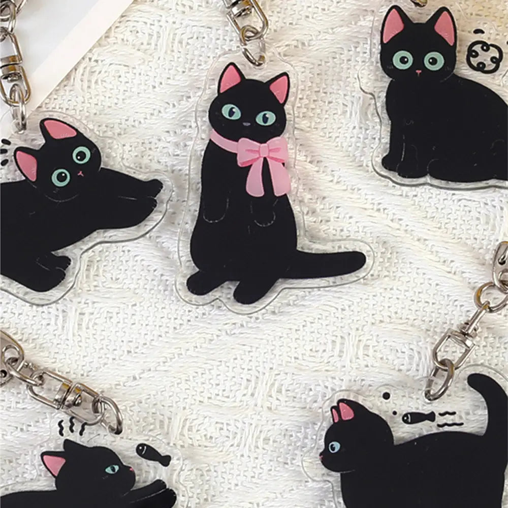 Clear acrylic black cat keychain with pink inner ears light blue eyes and pink bow designed as a cartoon animal bag charm.