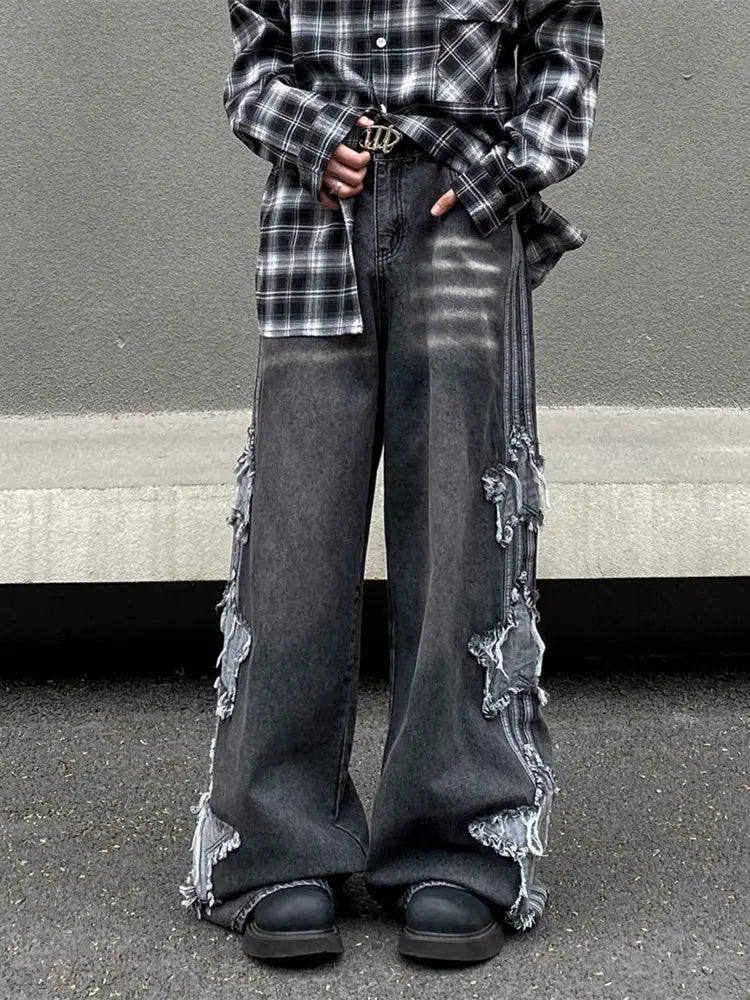 Jean denim wide-leg gris foncé avec des panneaux latéraux effilochés et délavés, et une boucle de ceinture métallique dans un style y2k baggy distressed denim jeans.