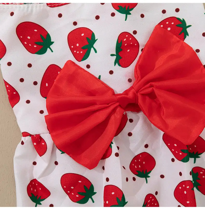 a floral dog princess dress featuring a vibrant red satin bow and white fabric with a playful strawberry pattern
