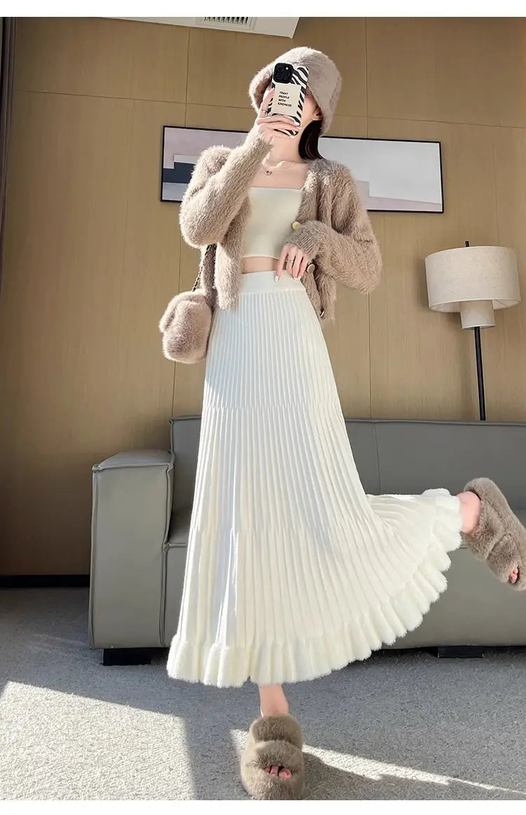 Une jupe mi-longue en maille blanche fluide, avec design parapluie à plis à taille haute, réalisée dans un tissu à texture douce.