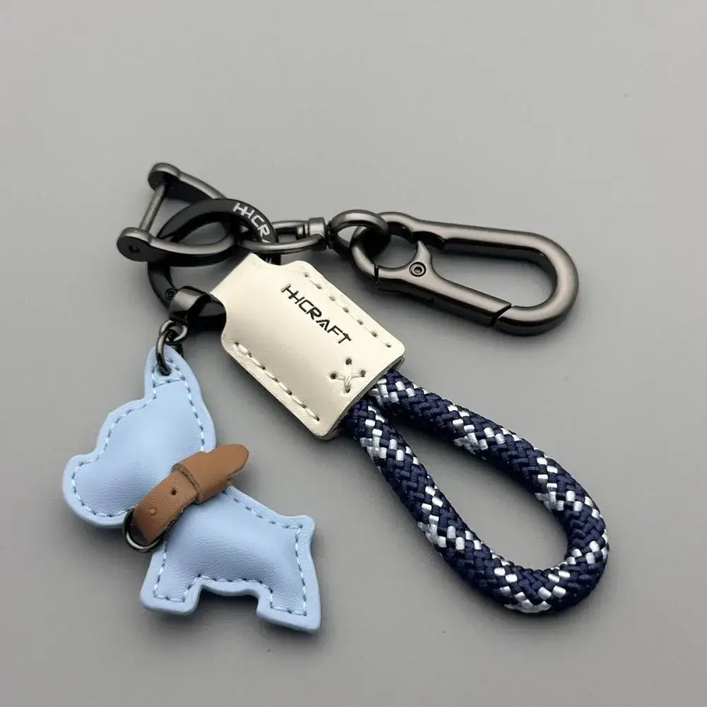 Light blue leather French Bulldog keychain with tan collar attached to navy and white braided rope strap and silver-toned metal hardware.