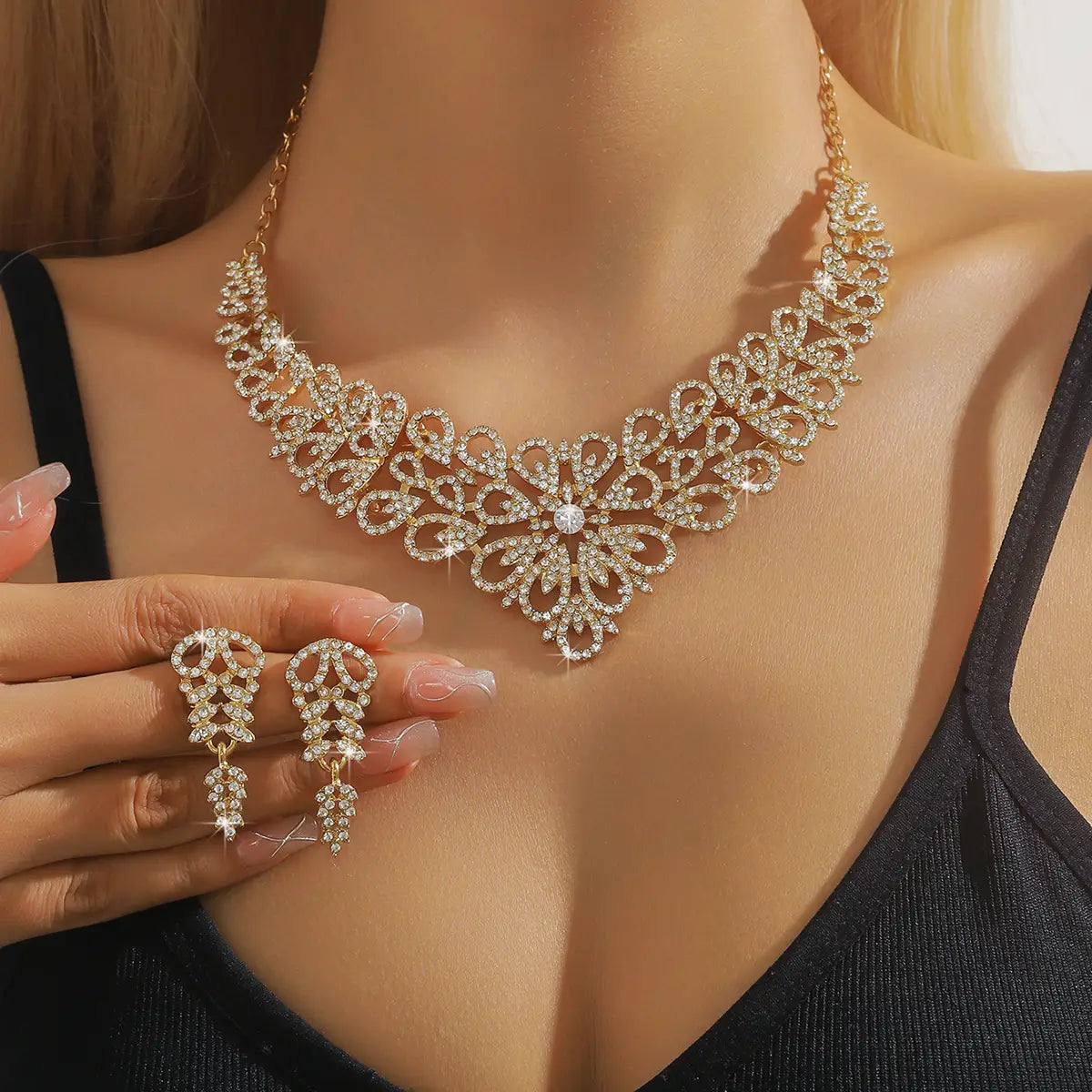Un ensemble de bijoux en forme de fleur en cristal rose plaqué or à la finition ton or, comprenant un collier au motif floral complexe, rehaussé de strass étincelants, ainsi que des boucles d’oreilles pendantes assorties.