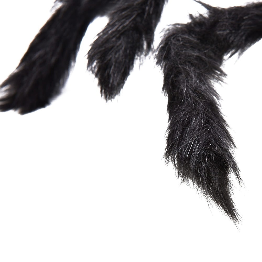 pattes d’araignée duveteuses noires fabriquées en fausse fourrure synthétique, dans le cadre de décorations d’Halloween avec de fausses araignées, avec un arrière-plan de toile d’araignée géante