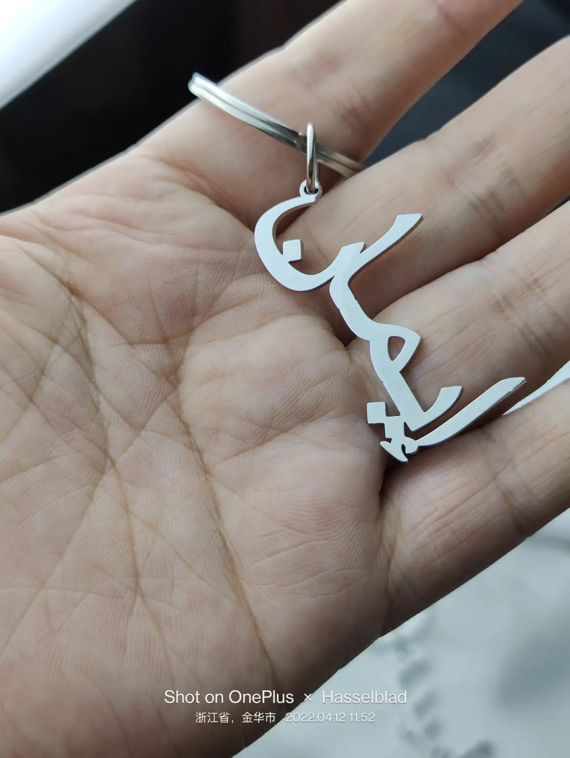 Llavero de nombre personalizado de metal plateado, hecho de acero inoxidable, con un diseño elegante de caligrafía árabe en estilo cursivo.