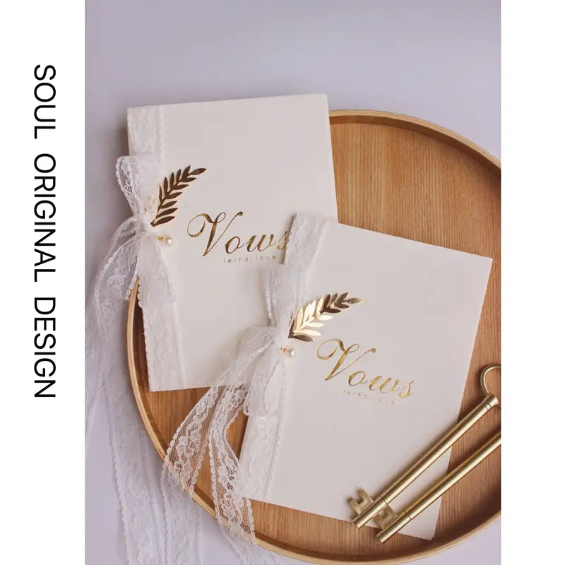 libro de votos de boda color blanco con letras en estilo caligrafía con lámina dorada, atado con una delicada cinta de encaje incluida en un conjunto de libros de votos de boda con llaves doradas y cintas