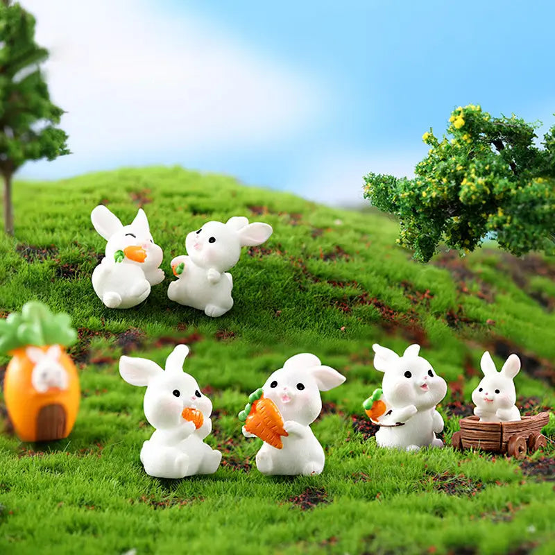 figurines miniatures de lapins en résine plastique blanche tenant des carottes orange, certaines assises dans un petit panier en bois, pour la décoration d’un jardin féerique