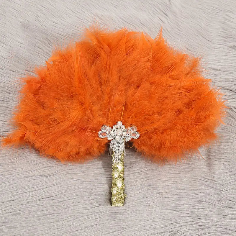 Ein Feder-Fächer für den Brauttanz bei der Hochzeit mit leuchtenden orangefarbenen Federn und einem funkelnden silber- und goldfarbenen Perlengriff.