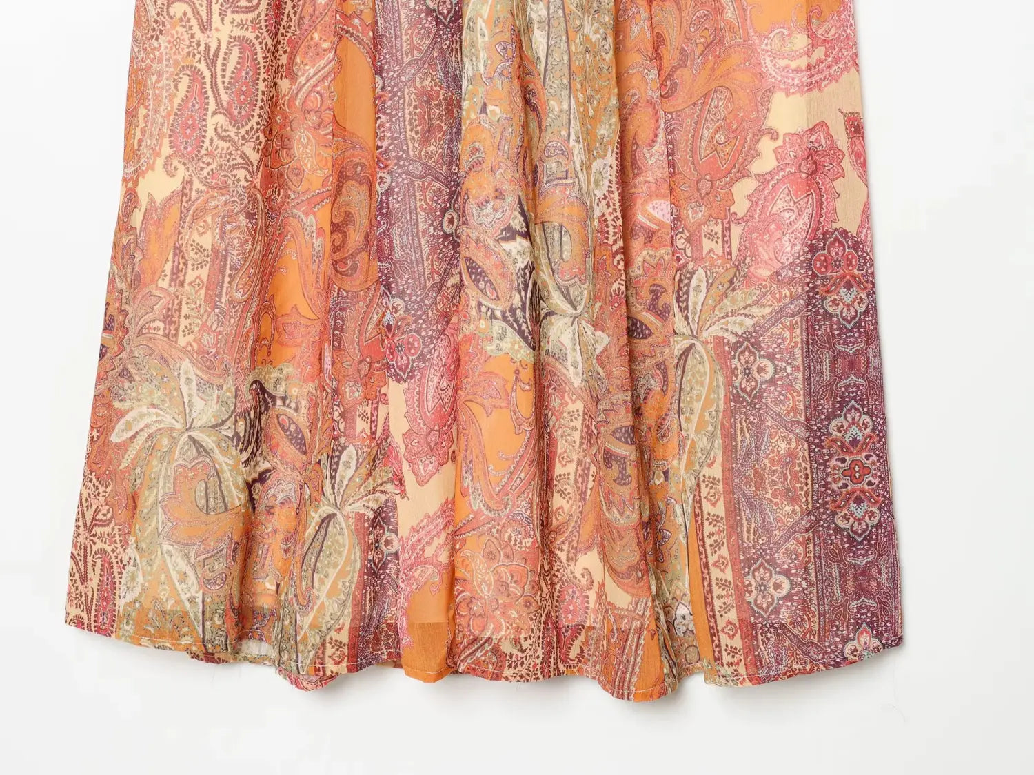 Jupe midi taille haute à imprimé cachemire, présentant un tissu léger fluide aux tons orange et rouille vibrants, avec des motifs floraux cachemire complexes.