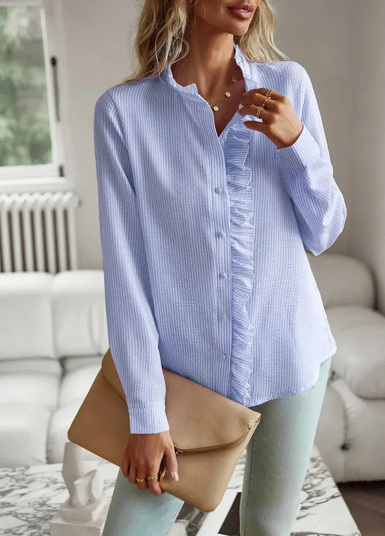 Blusa blanca de textura con manga larga que presenta rayas verticales azul claro y blancas, con canesú delantero con volantes.