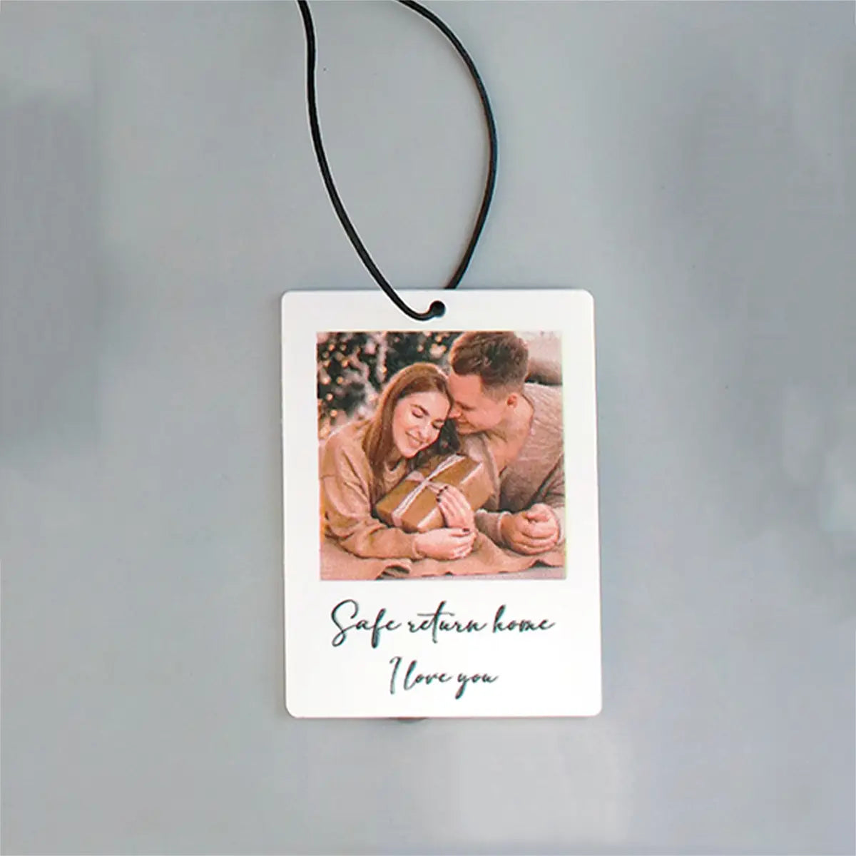 Weißer rechteckiger individueller Foto-Autoduft mit einem bedruckten Foto eines Paares und dem Text „safe return home i love you“ als personalisiertes Geschenk.