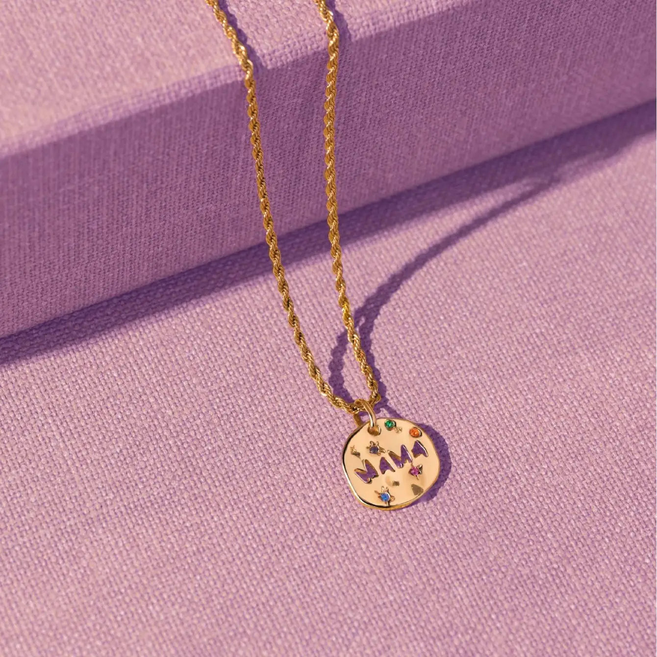 Collier en acier inoxydable doré avec pendentif en pierre précieuse « Mama », présentant un pendentif rond en forme de disque, gravé « Mama » et orné de pierres précieuses colorées.