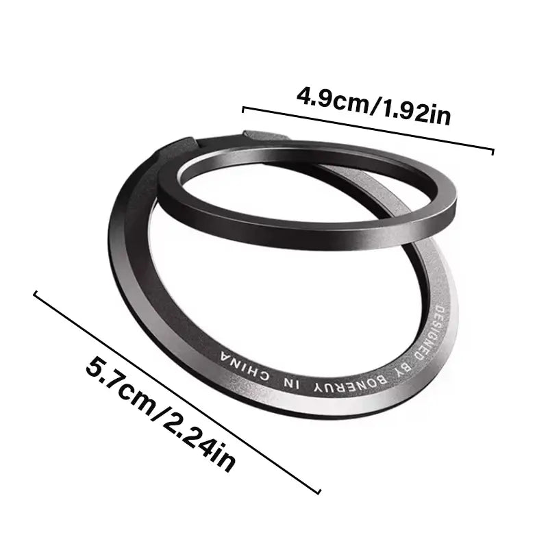 Anillo soporte metálico magnético negro para teléfono MagSafe con diseño moderno y elegante, y texto grabado a lo largo del borde interior.