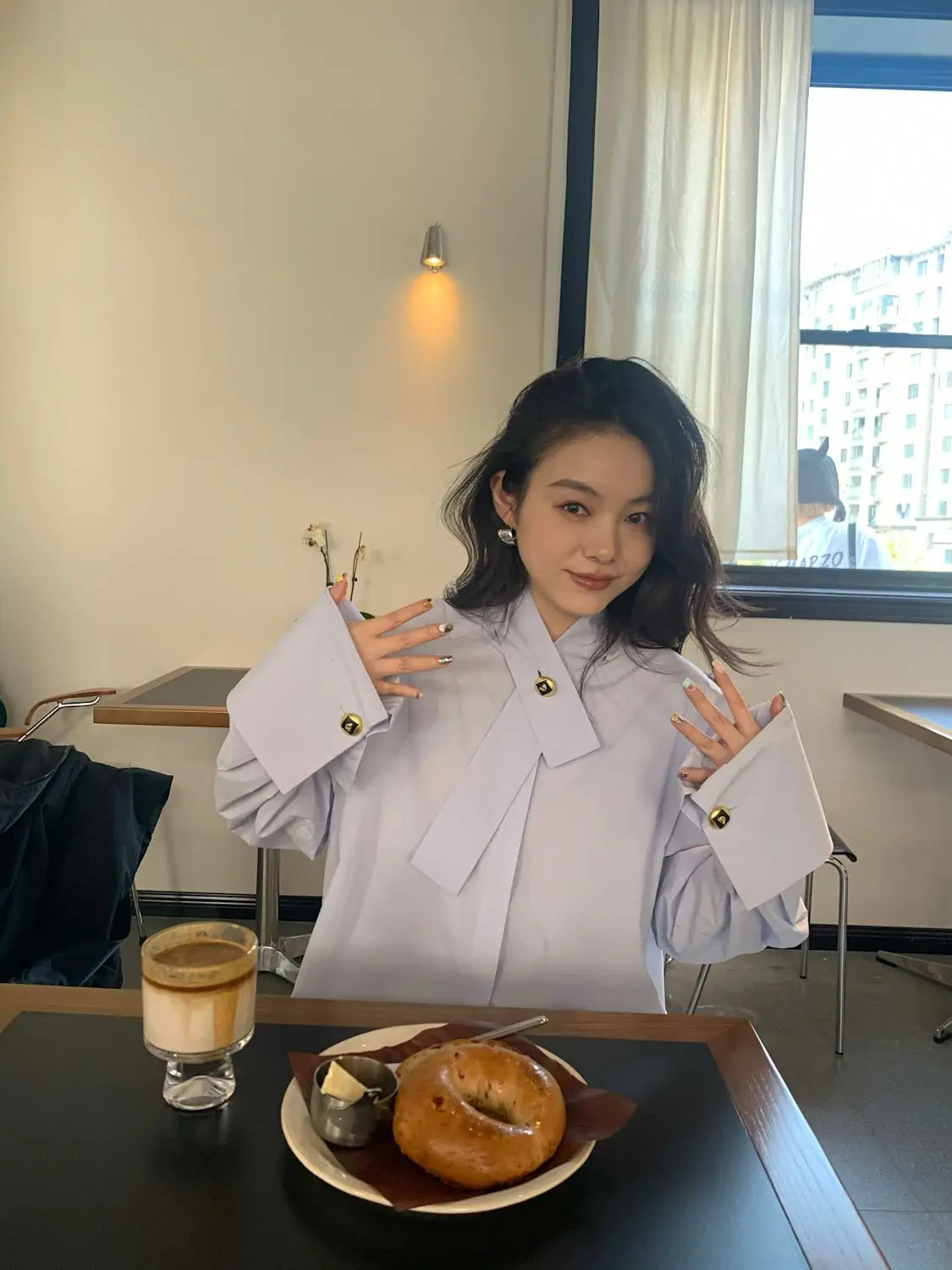 Light blue oversized button up shirt in light lavender fabric featuring long sleeves with wide cuffs and gold toned button details.