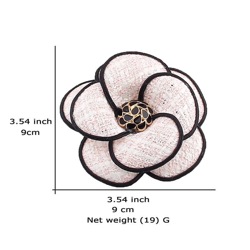 Brosche aus Kamelienstoff in Form einer Blume mit zartem hellweißem Stoff, schwarzen bestickten Rändern und einem goldfarbenen, geknüpften Perlenmittelteil für den Stil einer Retro-Damenbrosche.