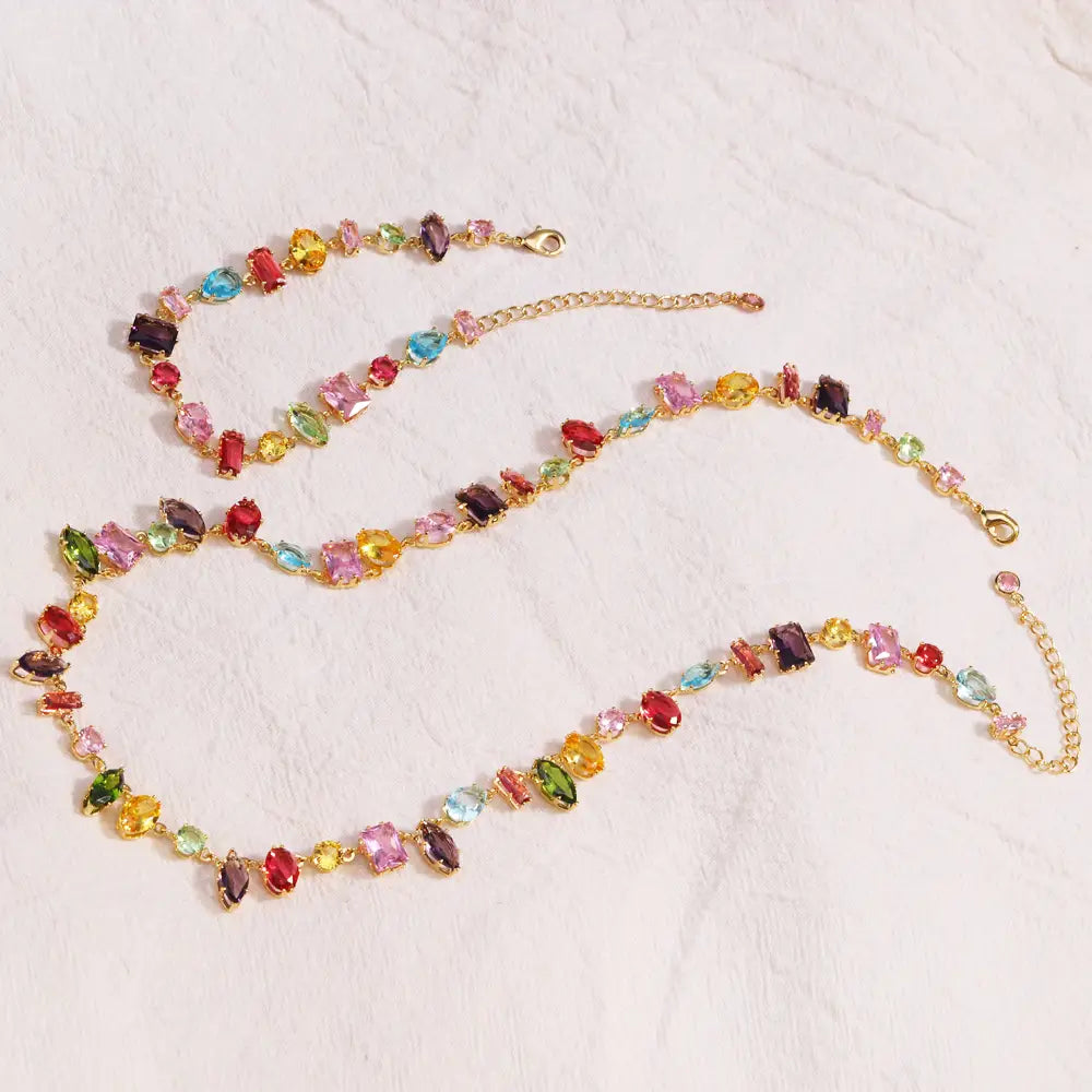 A vibrant gold plated necklace and matching bracelet set adorned with colorful faceted zircon crystals in red pink yellow green blue and purple.