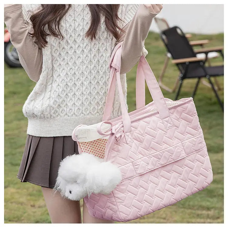 Sac cabas matelassé rose pour animal de compagnie avec des poignées assorties et un charme à pompon blanc duveteux, conçu comme un petit porte-chien respirant