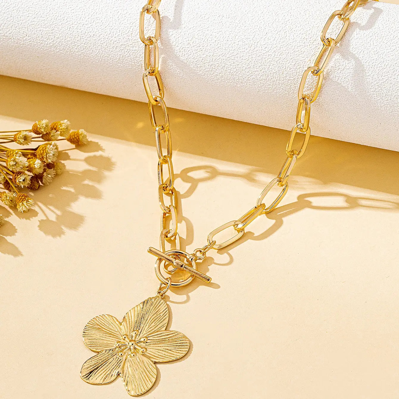 Collier pendentif plaqué or présentant un pendentif de fleur de glycine à cinq pétales détaillé avec une attache à bascule, style vintage pour femmes.