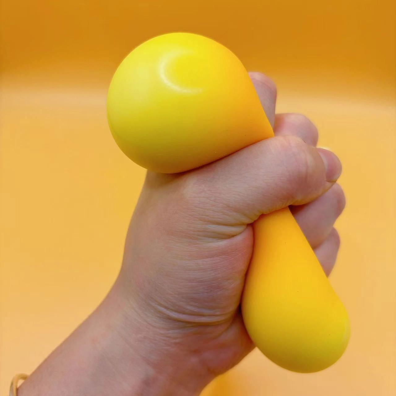 Un jouet antistress souple en forme de goutte, jaune vif, fabriqué en silicone lisse, vu de face, pour soulagement du stress et utilisation lors d’une fête d’anniversaire.