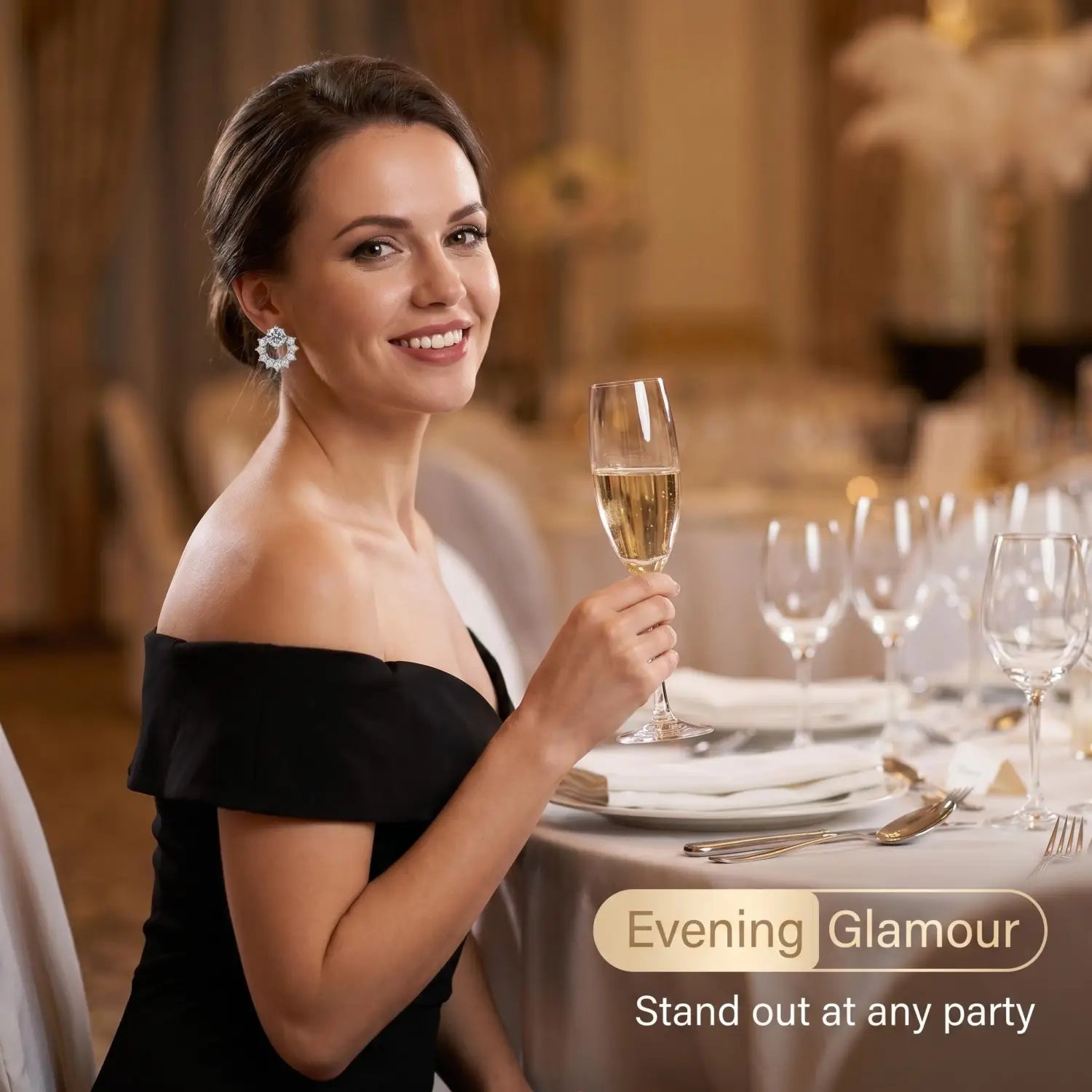 Une femme portant une robe noire dénudant les épaules sourit tout en portant des boucles d’oreilles clous en argent sterling serties de zircons et en tenant une coupe de champagne.