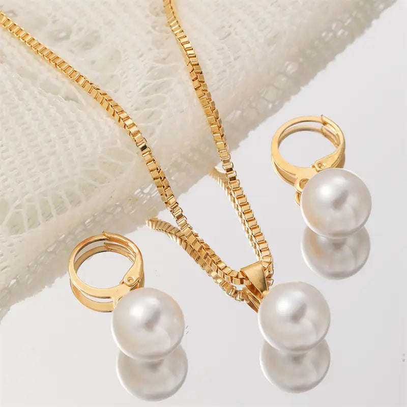 Gold-toned box chain necklace with a single pearl pendant and matching gold-tone hoop earrings featuring round pearls in a pearl jewelry set.