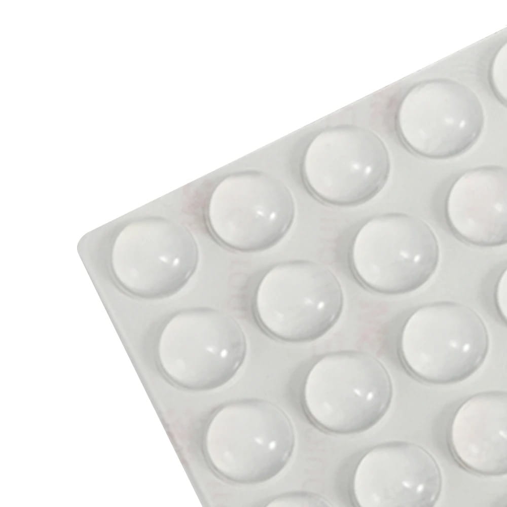 Pare-chocs d’armoire en silicone, lot de 100, présentant des pieds en caoutchouc blancs brillants en forme de dômes, disposés selon un motif en grille sur une feuille de support rectangulaire.