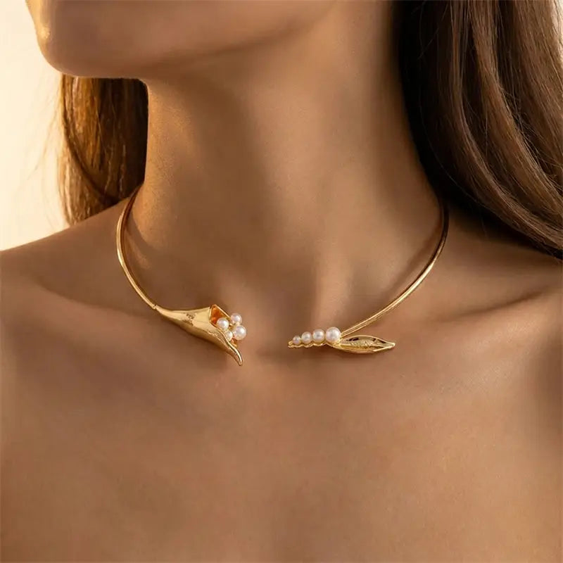 Chokerkette mit goldfarbenem Ton, florales Design mit offener Ausführung und zarten enden in Form von Blättern, verziert mit kleinen Perlen.