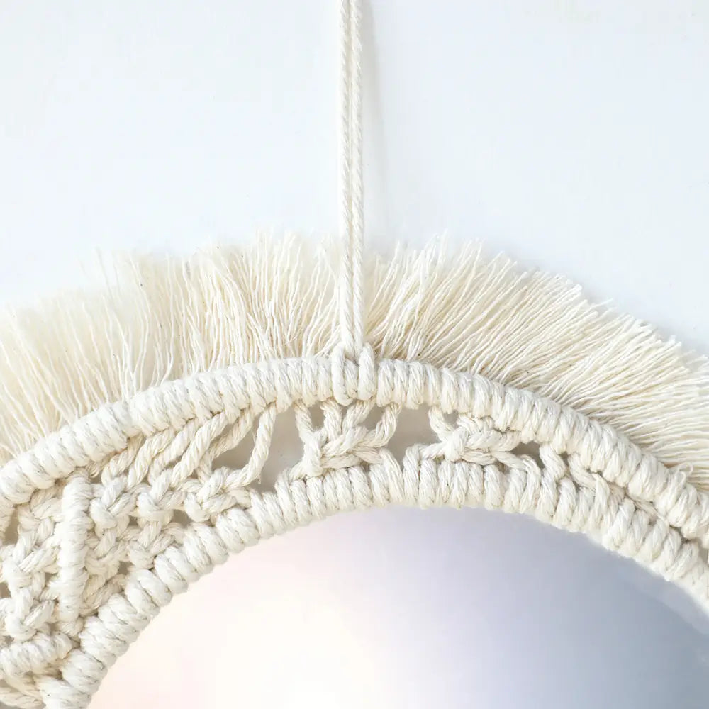 Cream-colored boho macrame wall mirror with intricate knotwork and fringe border ideal for living room home decor.