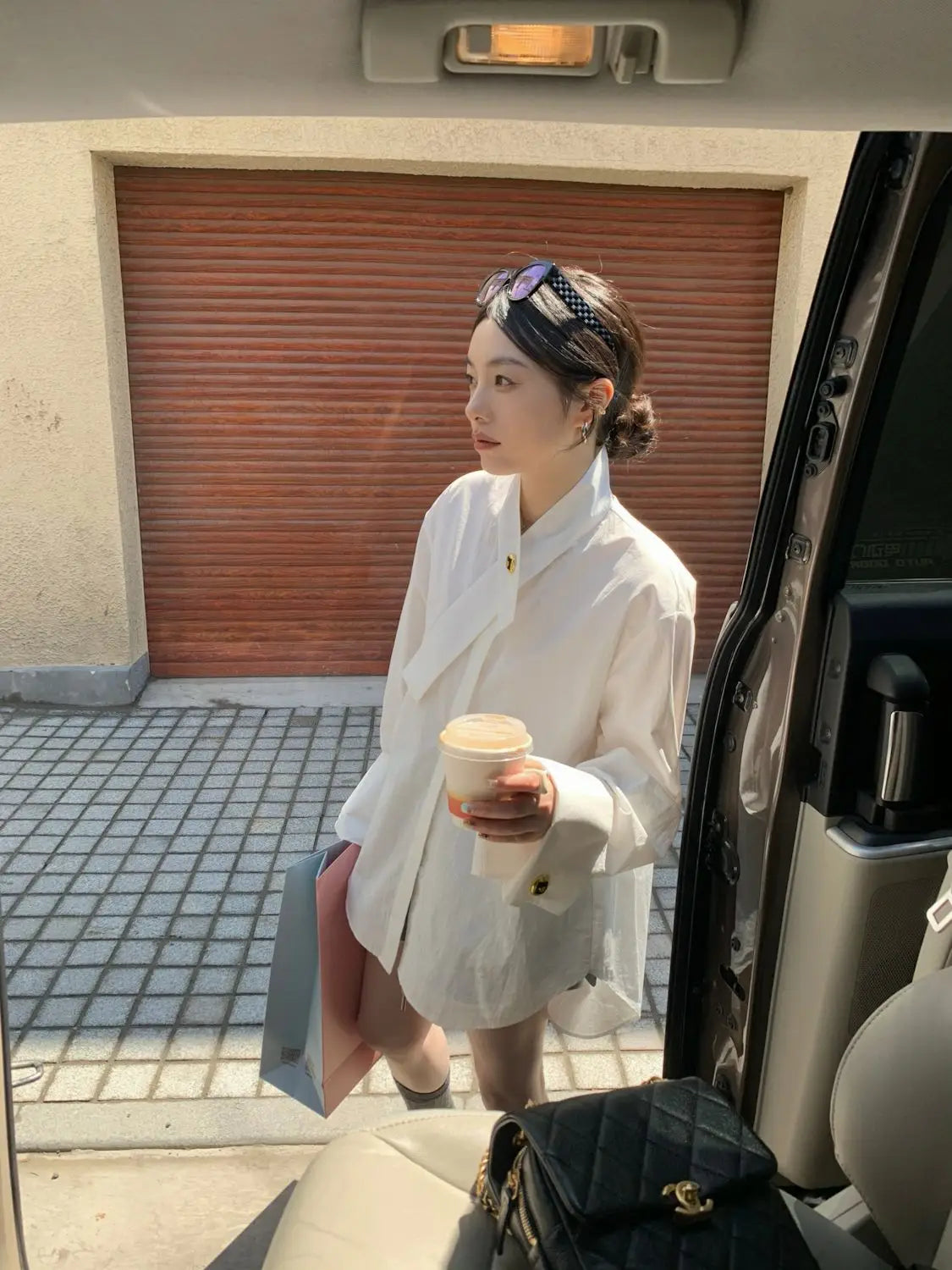 Light blue oversized button up shirt paired with a black quilted handbag featuring gold tone hardware and a classic interlocking logo.