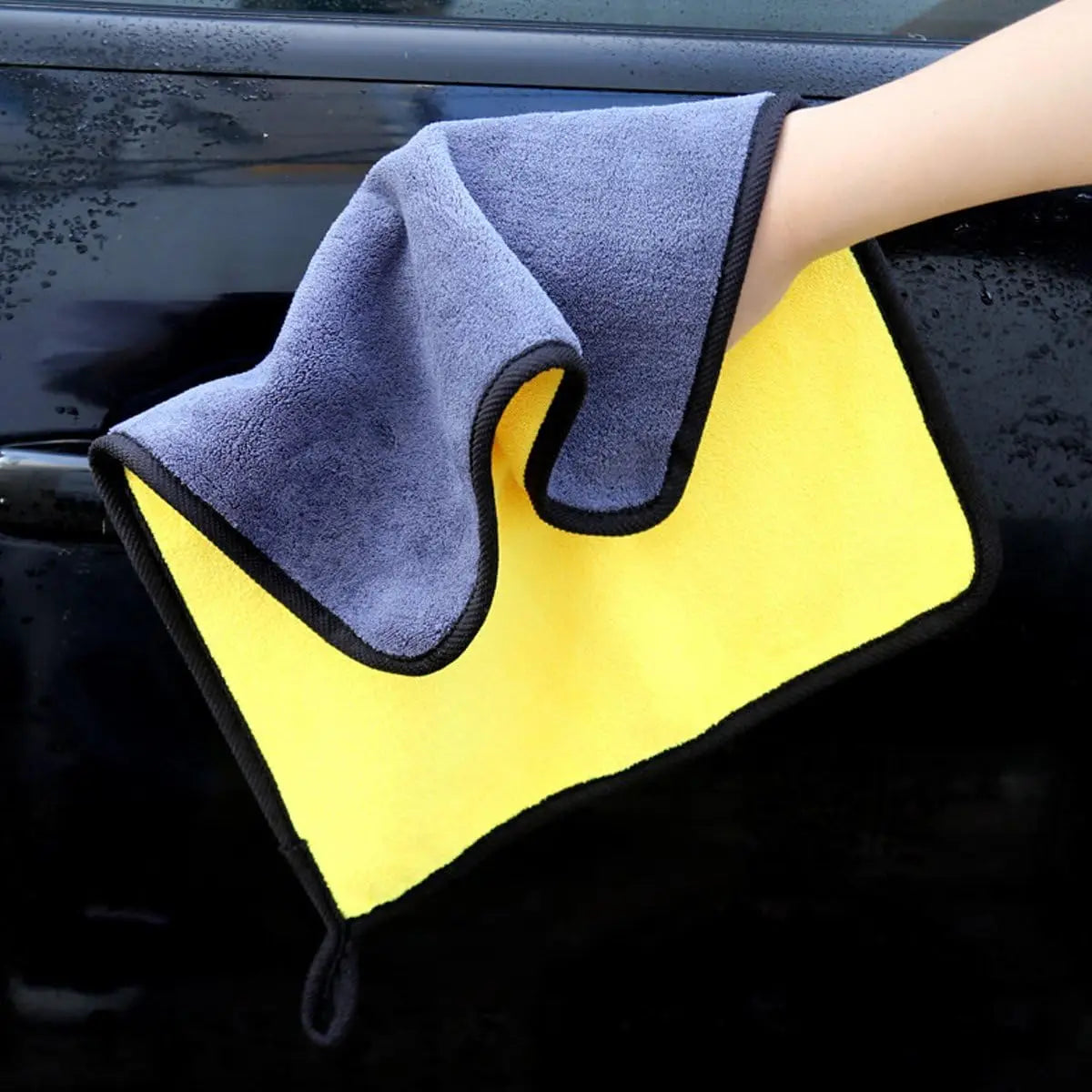 Chiffon de nettoyage en microfibres à double face en bleu marine et jaune vif, avec bordure noire, provenant d’un kit de nettoyage pour voiture et d’un ensemble de brosses de nettoyage.
